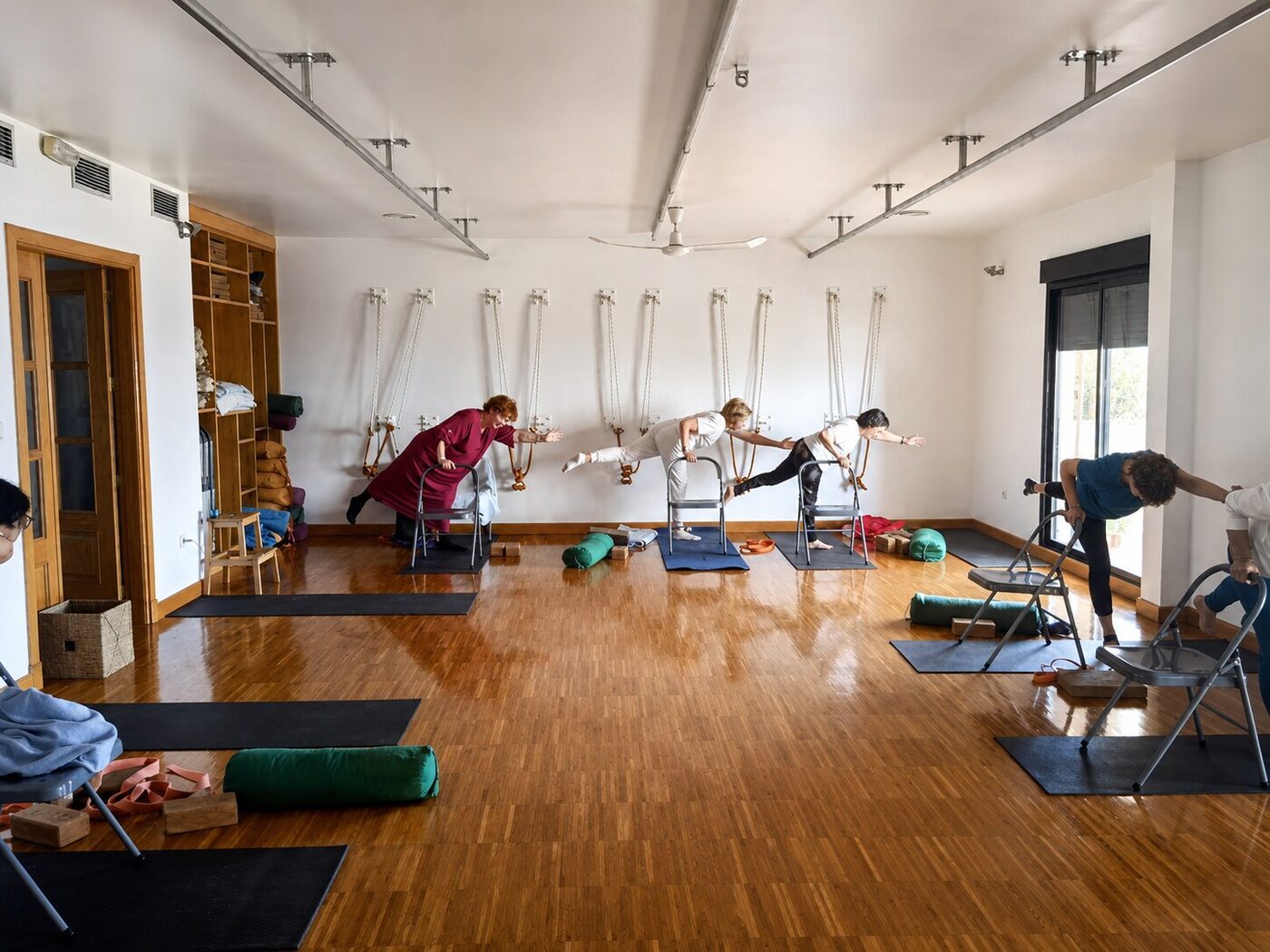 Practicantes de yoga adaptado con apoyo de silla y cuerdas de pared, en una extensión lateral