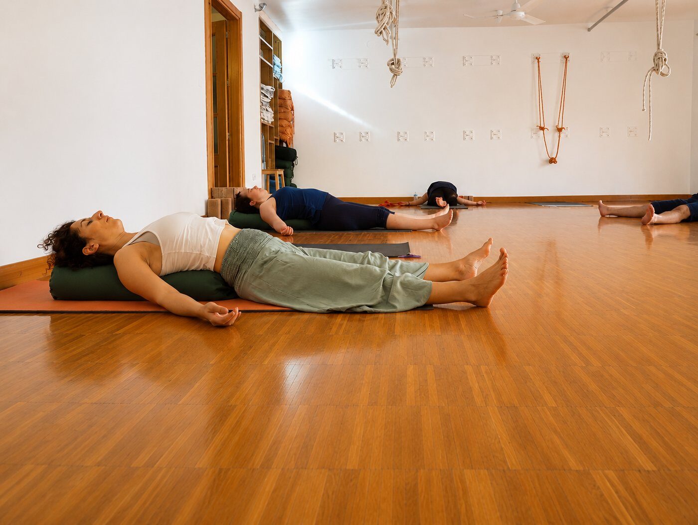 Practicantes en śavāsana, la postura de relajación final, tumbados sobre bolsters en la sala de Yoga Grund