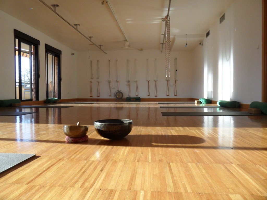 Sala de yoga con esterillas, cuencos tibetanos y luz natural